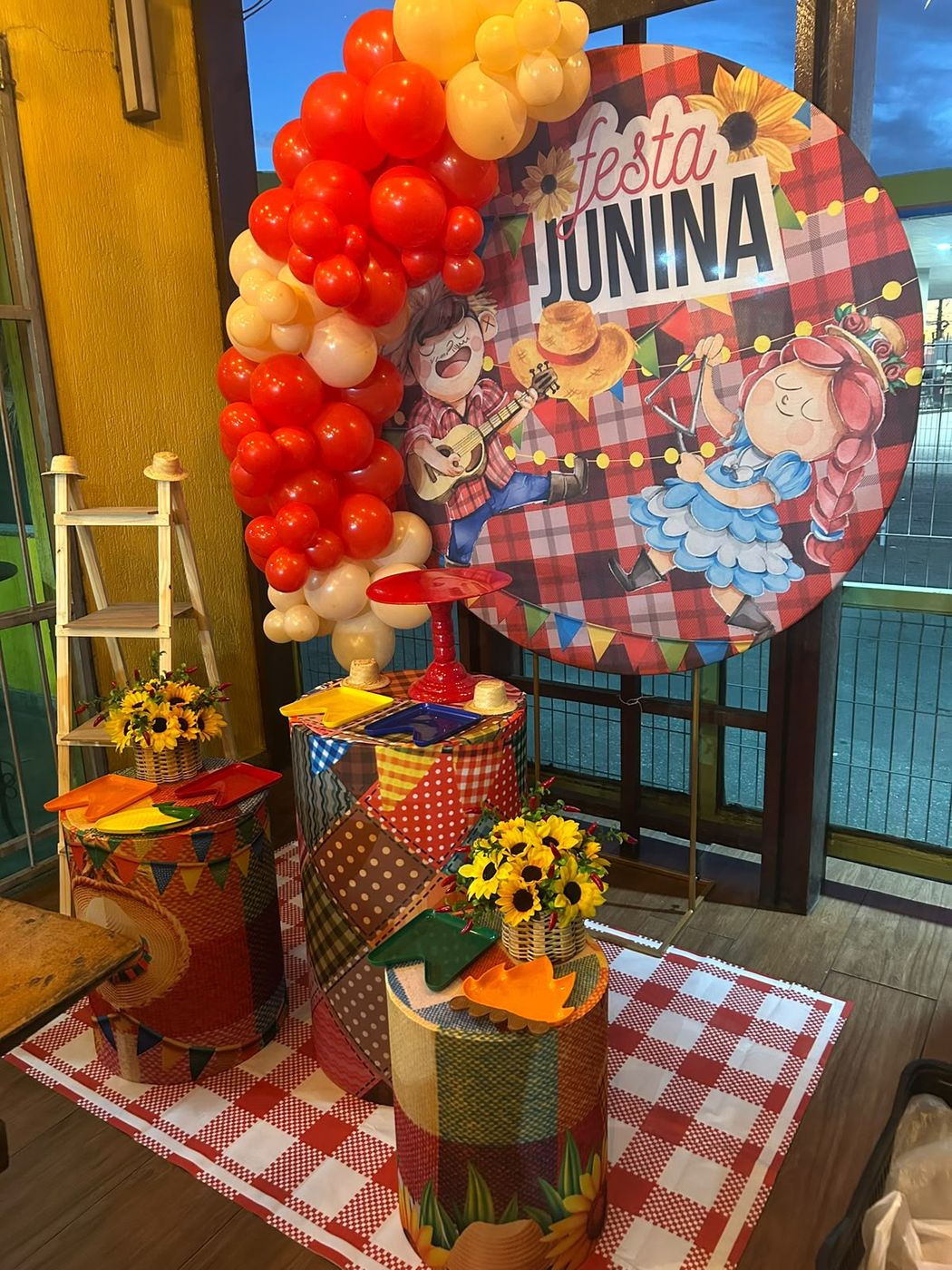 Decoração de Festa Junina com bandeirinhas, girassóis e balões vermelhos e amarelos
